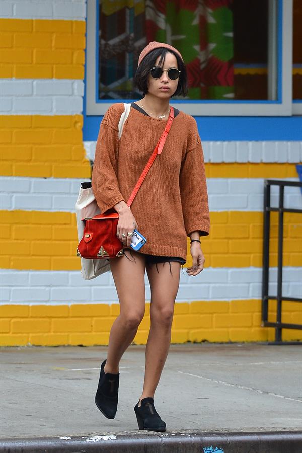 Zoe Kravitz walking in shorts and an orange top