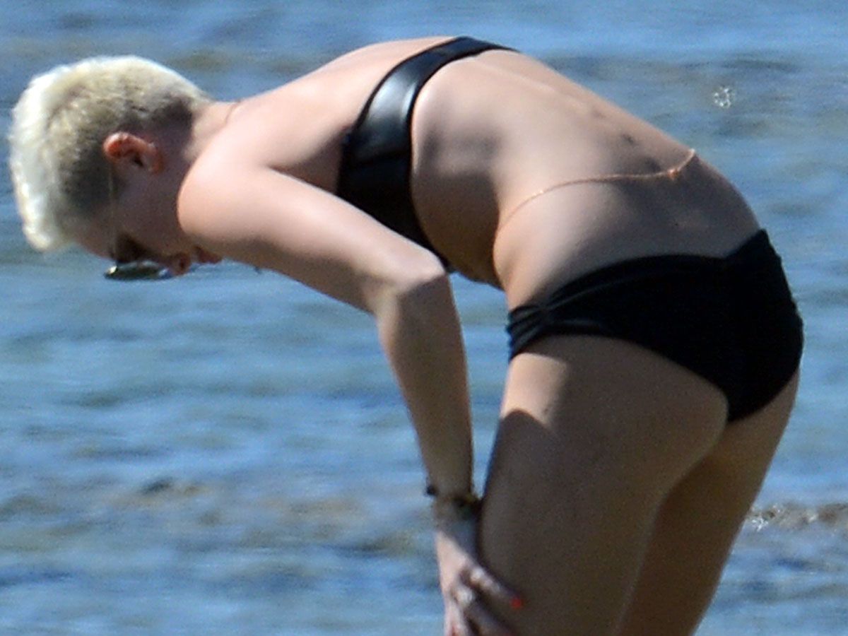 Miley Cyrus yoga in black bikini on beach in Hawaii 1/24/13. 