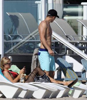 Paris Hilton at the beach in a skimpy red bikini and fishnet kaftan in Malibu.July 12, 2013