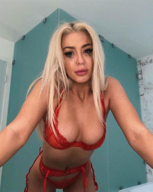 Tana Mongeau in sexy red lingerie showing off her big boobs cleavage in a bra and thong panties.