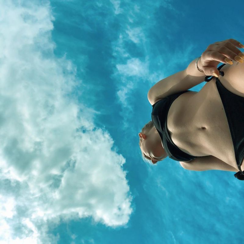 Jordyn Jones showing off her hot model body while standing outside in a sexy little black bikini photographed from below.